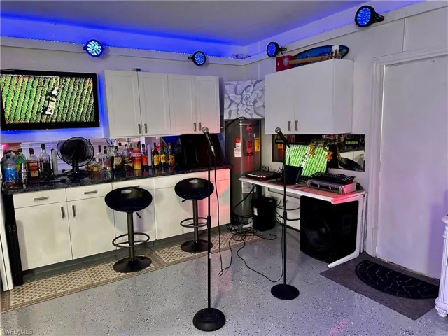 Bar with white cabinetry and dark stone countertops