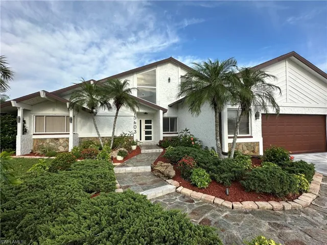 View of front of home featuring stone siding, a garage, stucco siding, and driveway