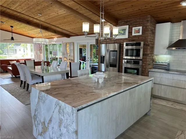 Kitchen featuring light stone countertops, wood ceiling, french doors, stainless steel appliances, and decorative backsplash