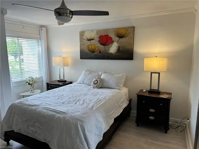Bedroom featuring wood finished floors, ornamental molding, and a ceiling fan