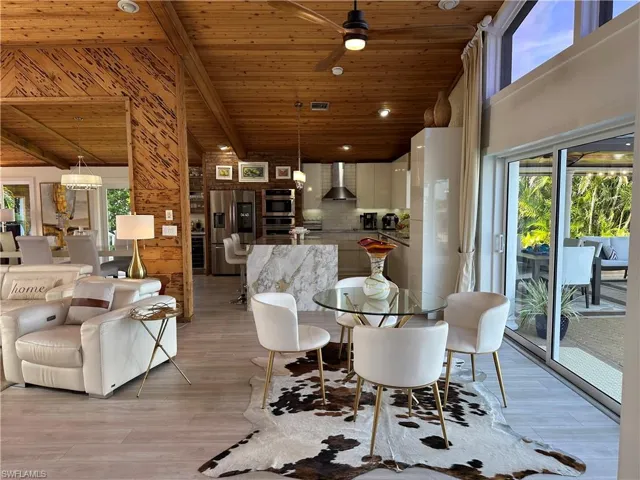 Dining area with healthy amount of natural light, light wood-style flooring, a ceiling fan, wooden ceiling, and lofted ceiling with beams