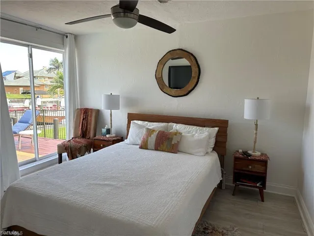 Bedroom with wood finished floors, ceiling fan, access to exterior, a textured ceiling, and a textured wall