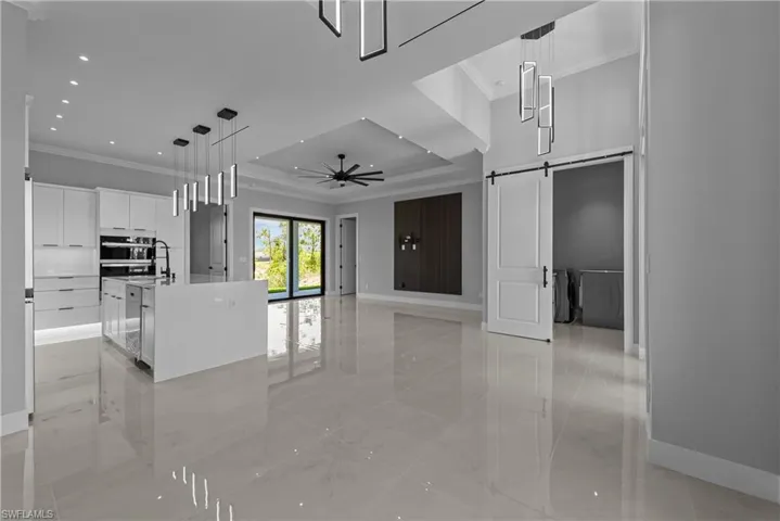 Kitchen with crown molding, a barn door, baseboards, white cabinets, and recessed lighting