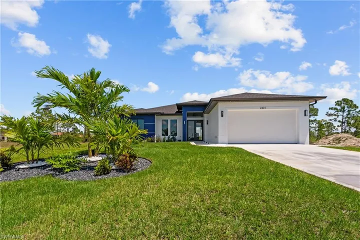 Prairie-style home featuring stucco siding, a garage, concrete driveway, and a front yard