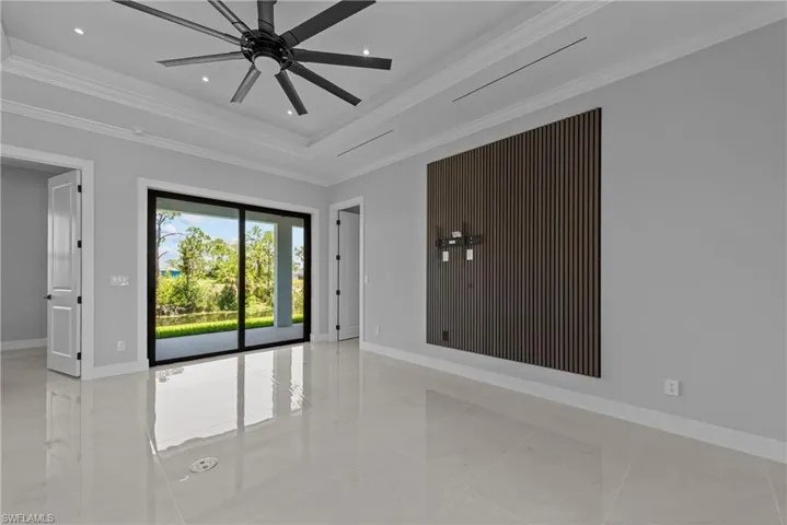 Empty room featuring baseboards, ornamental molding, a ceiling fan, recessed lighting, and a tray ceiling