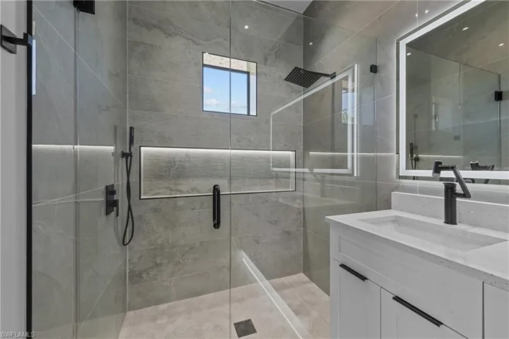 Full bathroom with a stall shower, vanity, and tile walls