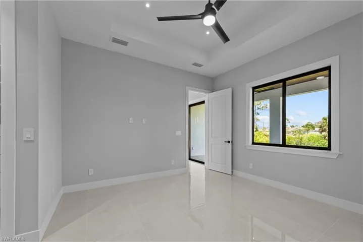 Empty room featuring a tray ceiling, ceiling fan, baseboards, and recessed lighting