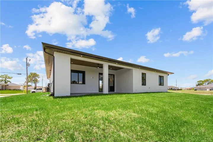 Back of house featuring stucco siding and a lawn
