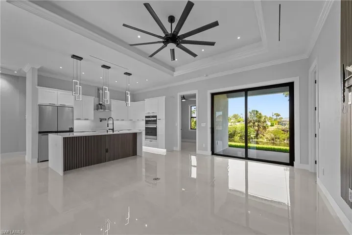 Kitchen featuring a ceiling fan, stainless steel appliances, white cabinetry, a spacious island, and a sink