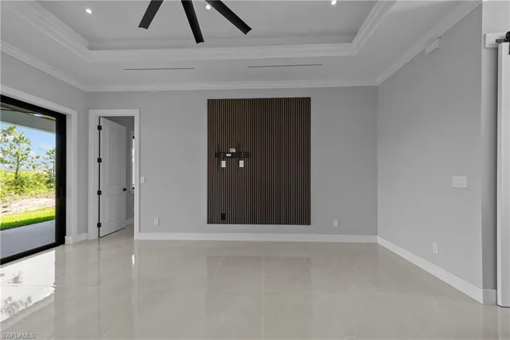 Empty room featuring a tray ceiling, baseboards, ornamental molding, and a ceiling fan