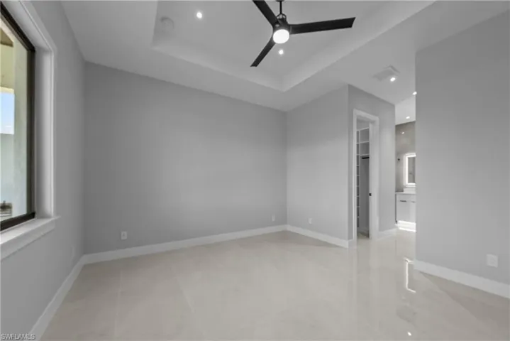 Unfurnished room with a ceiling fan, recessed lighting, a smoke detector, a raised ceiling, and baseboards