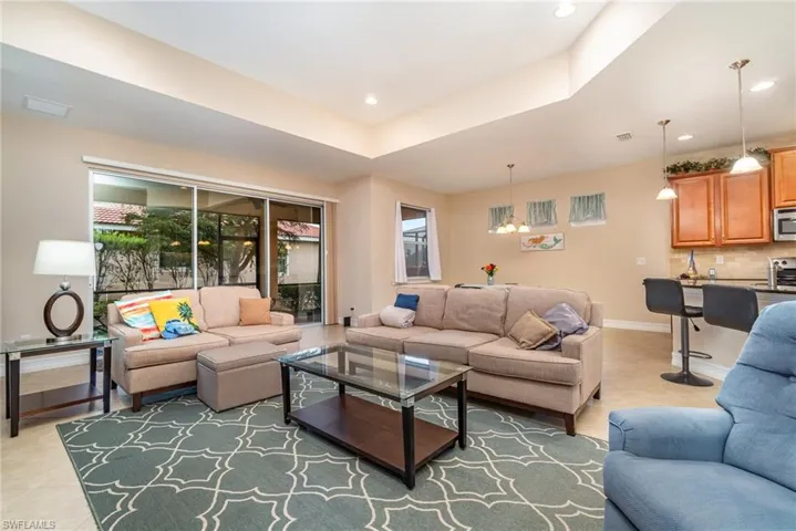 Open concept view of living room into kitchen, breakfast area and triple sliders to covered lanai.