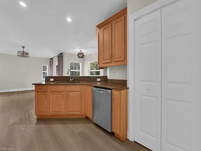 Kitchen with stone countertops, brand new dishwasher, light wood-style flooring, a peninsula with bar seating, light wood finish cabinets and pantry