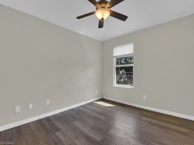 Empty spare room featuring dark wood-type flooring and ceiling fan