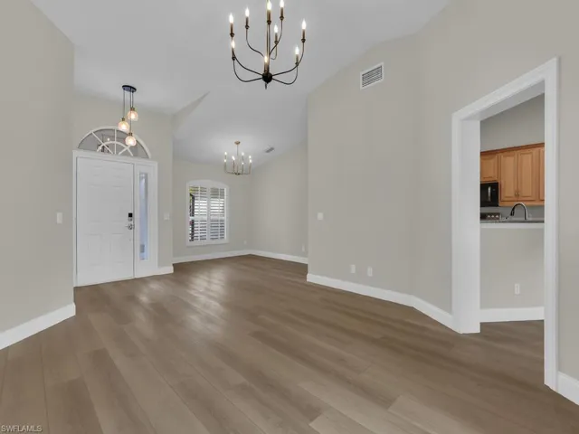 Foyer with suspended lighting, light wood-type flooring, and vaulted ceiling