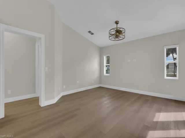 Living room featuring lofted ceiling, light wood finished floors, and a fandelier
