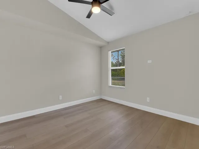 Spare room featuring vaulted ceiling, a ceiling fan, and wood finished floors