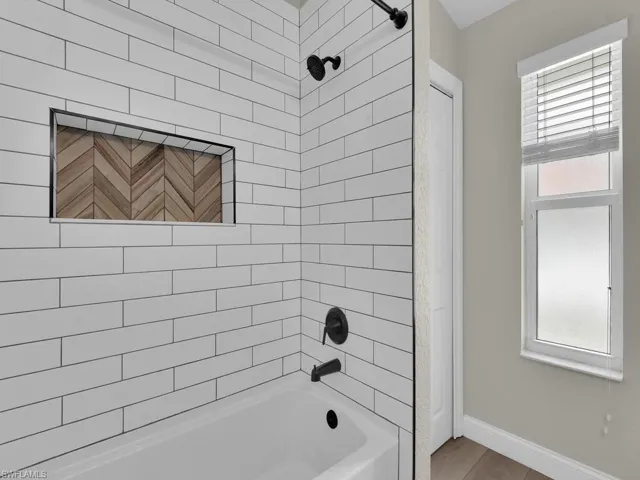 Full guest bathroom featuring an abundance of natural light, NEW tub / shower combination, black hardware and light newer wood finished floors