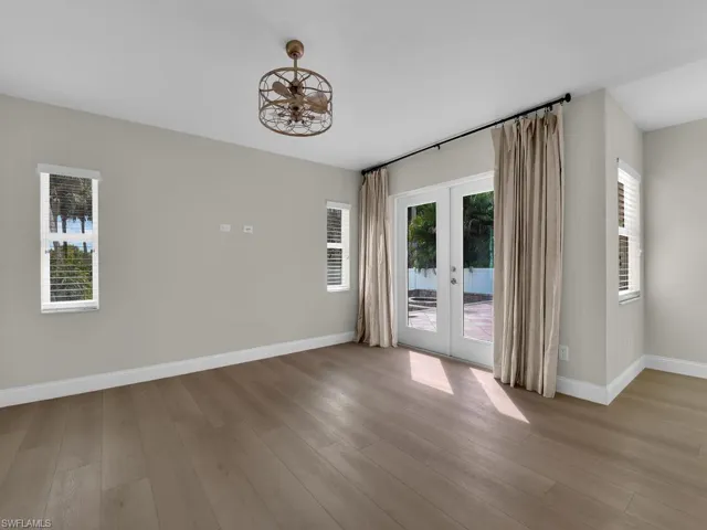 Light & Spacious living room with french doors leaving to outside paved deck and fireplace area.