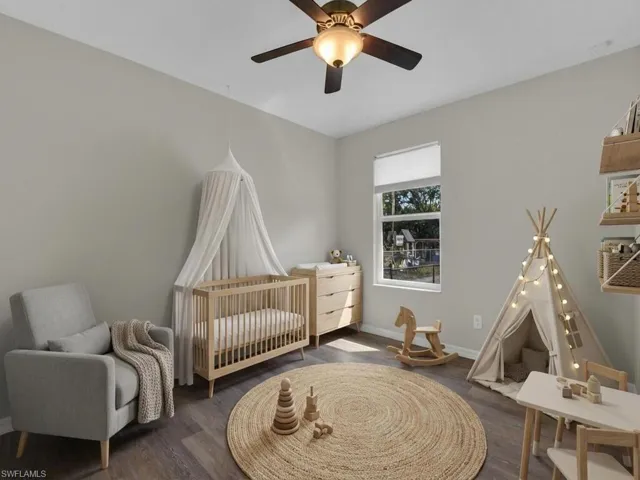 Bedroom with a nursery area (AI Generated), dark wood-style floors, and ceiling fan