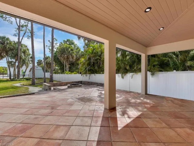 Fenced backyard featuring a paved deck & an outdoor fire pit.