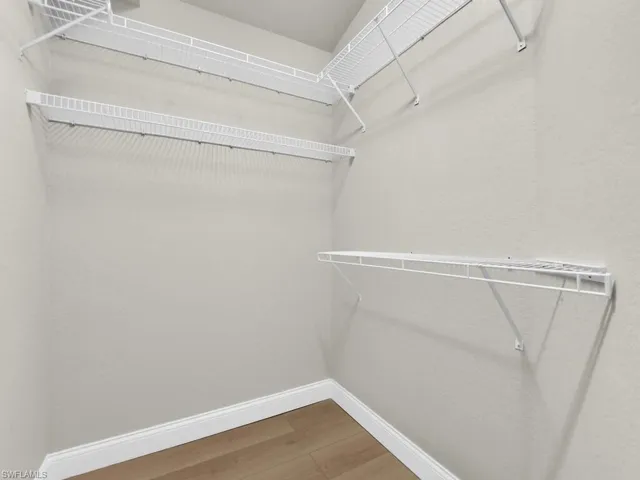 Master Walk in closet featuring light wood finished floors and lots of light