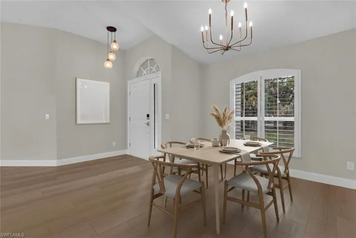 Dining space featuring wood finished floors, suspended lighting, and vaulted ceiling *AI GENERATED FURNISHINGS*