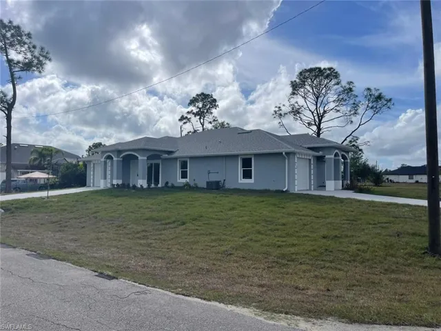 Ranch-style home featuring central AC unit, a garage, and a front lawn