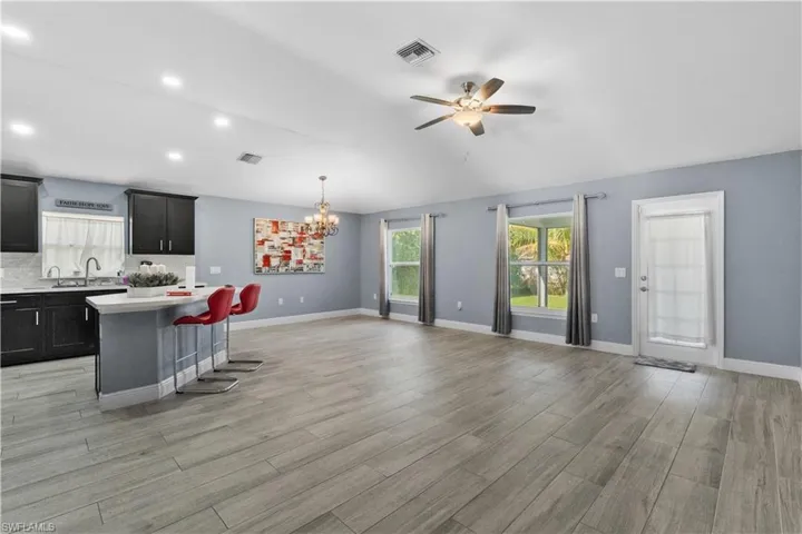 Kitchen featuring a kitchen bar, a chandelier, dark cabinets, pendant lighting, and a ceiling fan