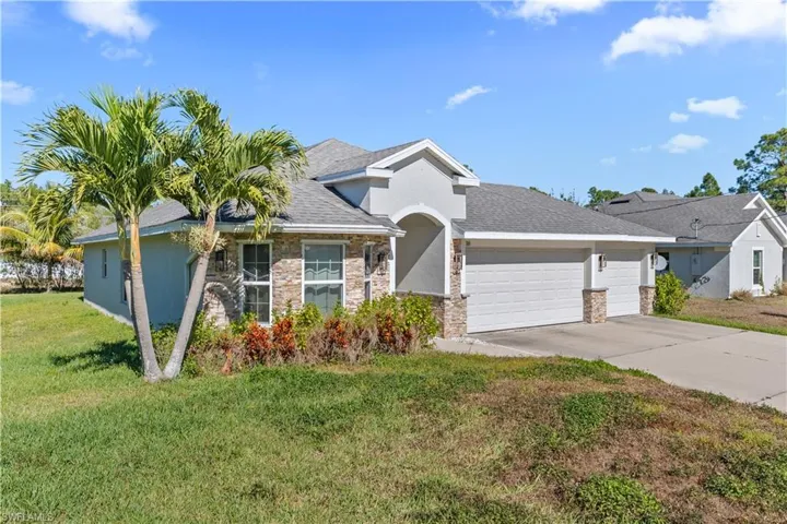 Ranch-style home featuring a garage, concrete driveway, a front yard, and roof with shingles