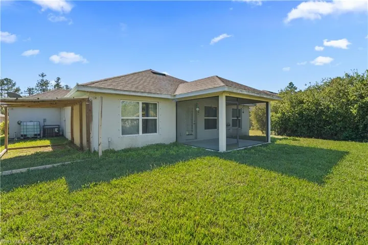 Back of house with a lawn, stucco siding, roof with shingles, and a sunroom