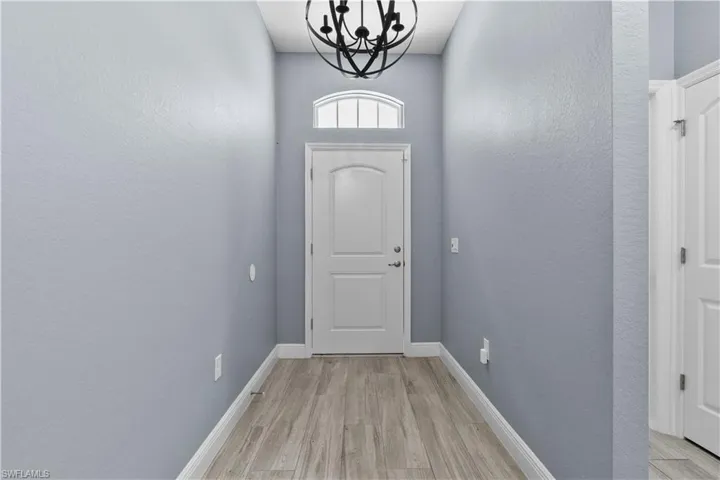 Entryway with a chandelier, wood finished floors, and a textured wall