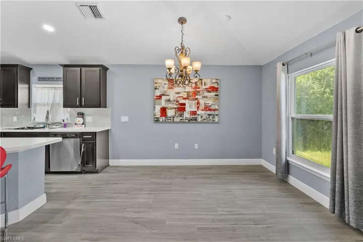 Kitchen featuring a chandelier, tasteful backsplash, stainless steel dishwasher, pendant lighting, and plenty of natural light