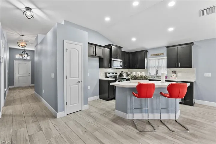 Kitchen with a center island, vaulted ceiling, dark cabinets, a breakfast bar area, and backsplash
