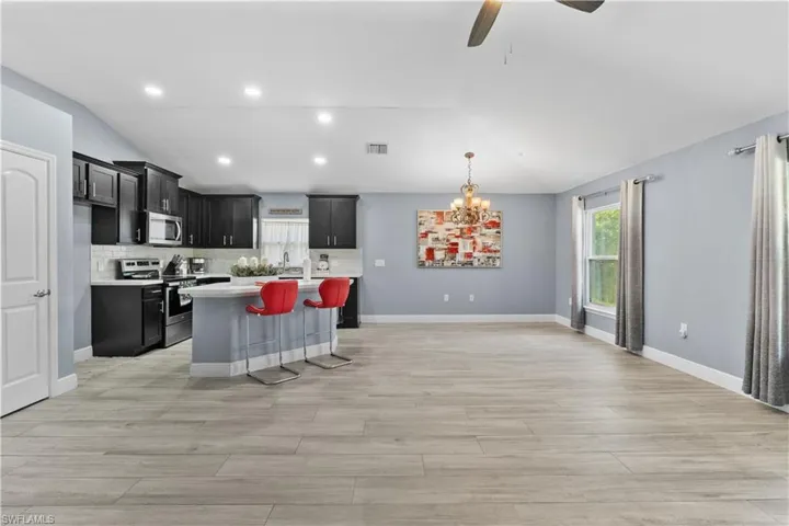 Kitchen with lofted ceiling, appliances with stainless steel finishes, a kitchen island, a breakfast bar area, and dark cabinetry