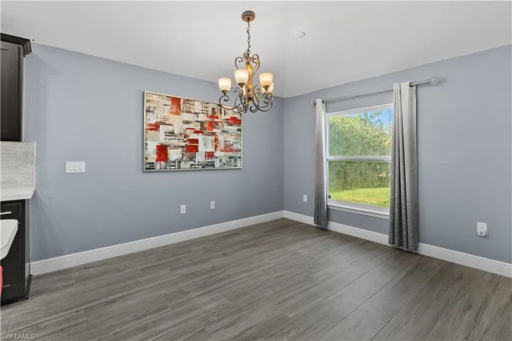 Unfurnished dining area featuring a chandelier and dark wood-style flooring