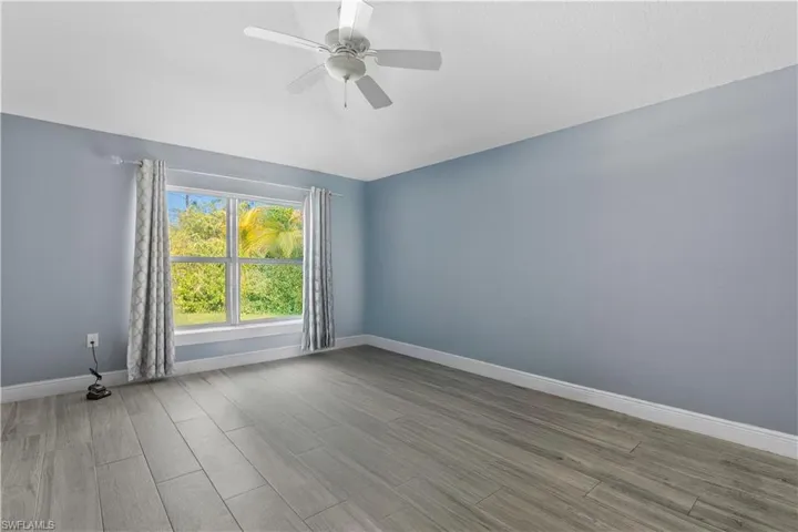 Unfurnished room with wood finish floors, lofted ceiling, and ceiling fan