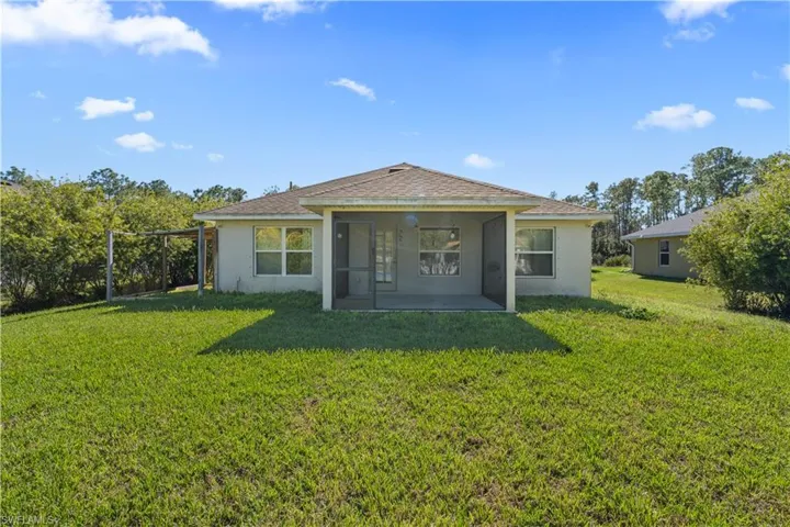 Rear view of house with stucco siding, a patio area, and a lawn