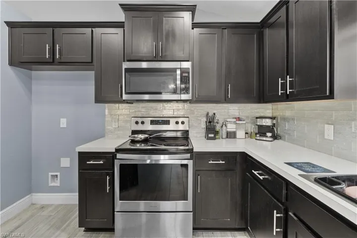 Kitchen with stainless steel appliances, light countertops, tasteful backsplash, and light wood finished floors