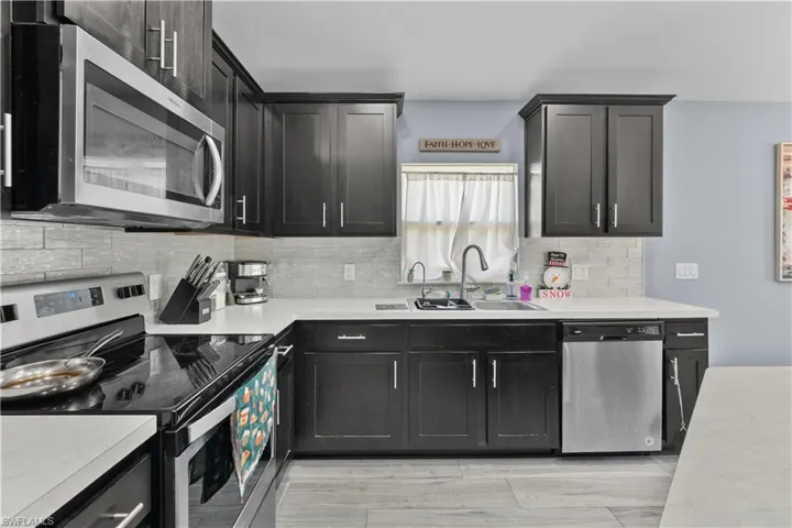 Kitchen with stainless steel appliances, light countertops, and decorative backsplash
