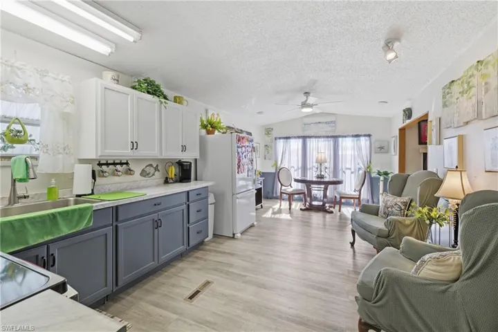 Kitchen featuring white cabinetry, light countertops, gray cabinetry, lofted ceiling, and a textured ceiling