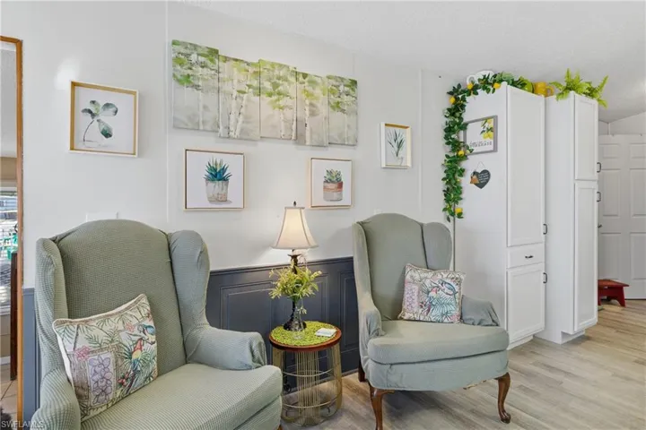 Living area featuring a decorative wall, wainscoting, light wood-type flooring, and a textured ceiling