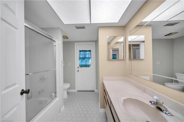 Full bathroom with vanity, enclosed tub / shower combo, and light tile patterned floors
