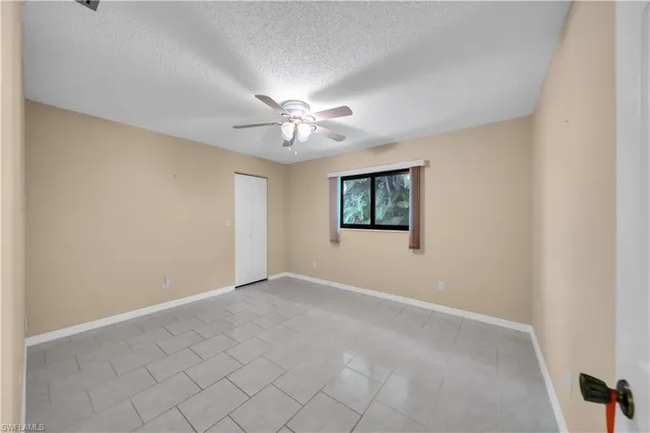 Unfurnished room with light tile patterned flooring, a textured ceiling, and ceiling fan