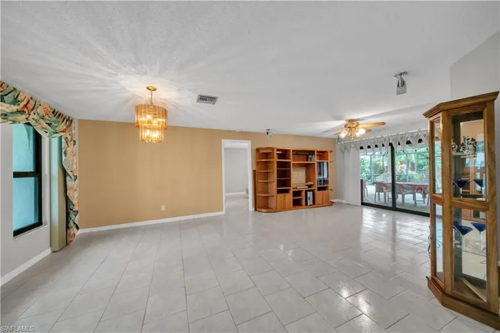 Unfurnished living room featuring a chandelier, a textured ceiling, light tile patterned flooring, and ceiling fan