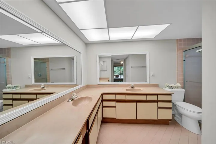 Bathroom featuring light tile patterned flooring, double vanity, and a shower stall