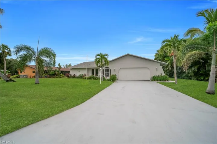 Ranch-style home with stucco siding, an attached garage, driveway, and a front lawn