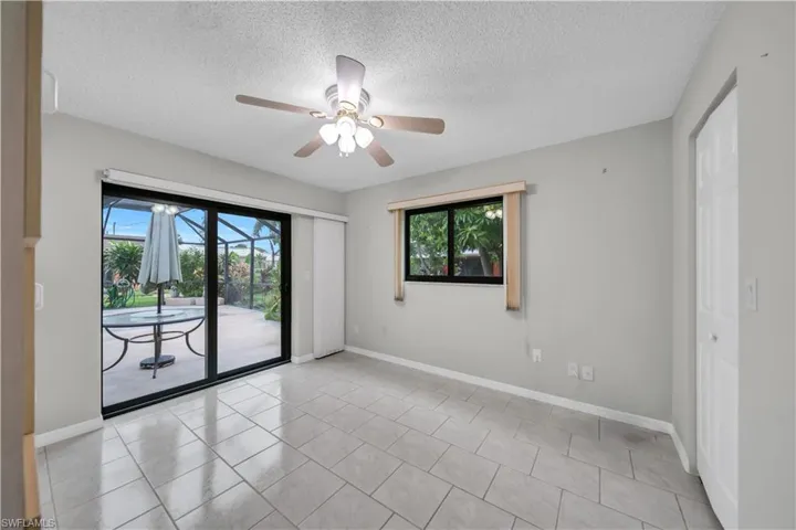 Empty room featuring a textured ceiling, light tile patterned flooring, a ceiling fan, and a sunroom