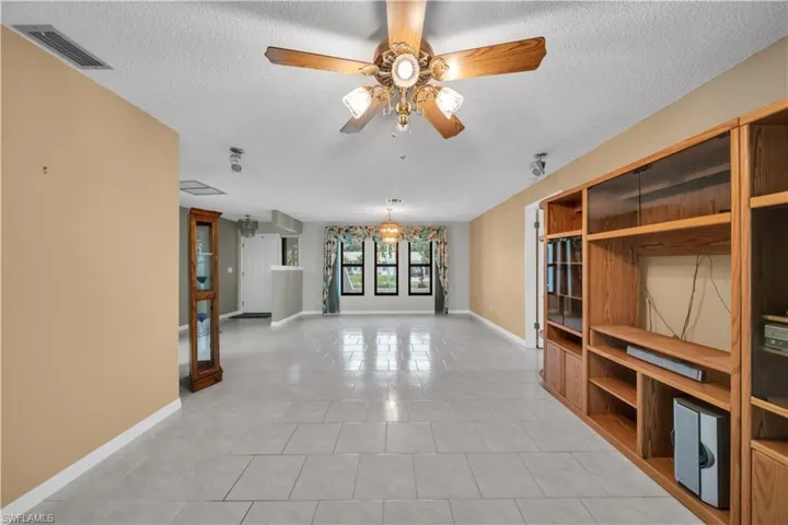 Unfurnished living room with light tile patterned flooring, a textured ceiling, and a ceiling fan