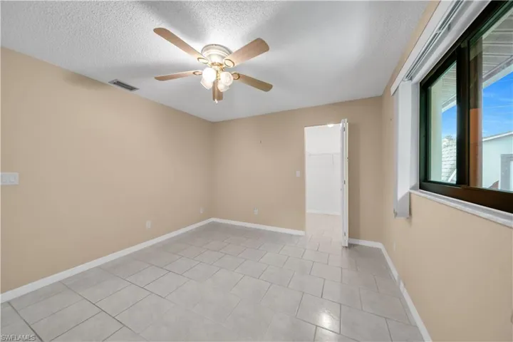 Unfurnished room with a textured ceiling, light tile patterned floors, and a ceiling fan